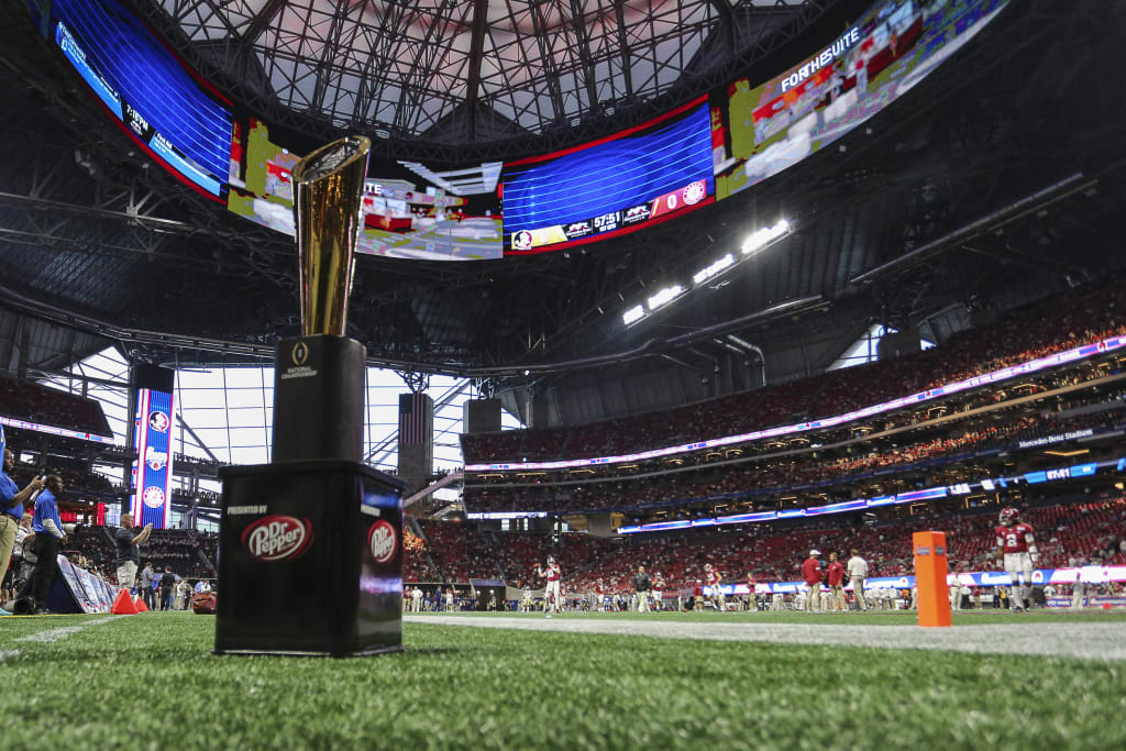 ATLANTA TO HOST 2025 COLLEGE FOOTBALL PLAYOFF NATIONAL CHAMPIONSHIP 1 A football stadium with a large trophy on the field and a crowd in the stands in Atlanta, Georgia.