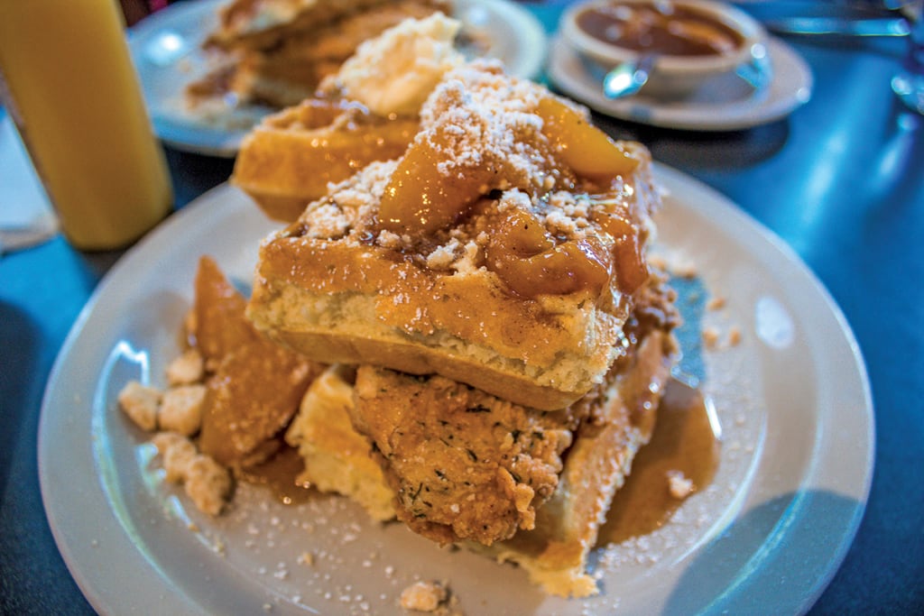 Stacked waffles topped with fried chicken, syrup, and powdered sugar on a plate in Atlanta, Georgia.