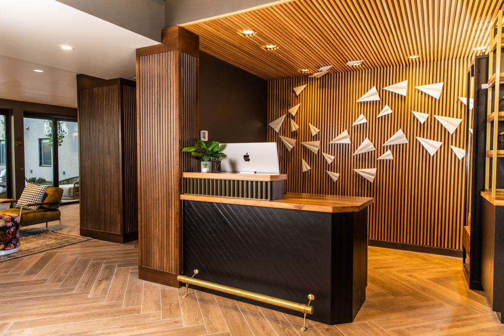 Modern reception desk with wooden counter and black base, featuring an Apple iMac and decorative paper airplanes in Atlanta, Georgia.