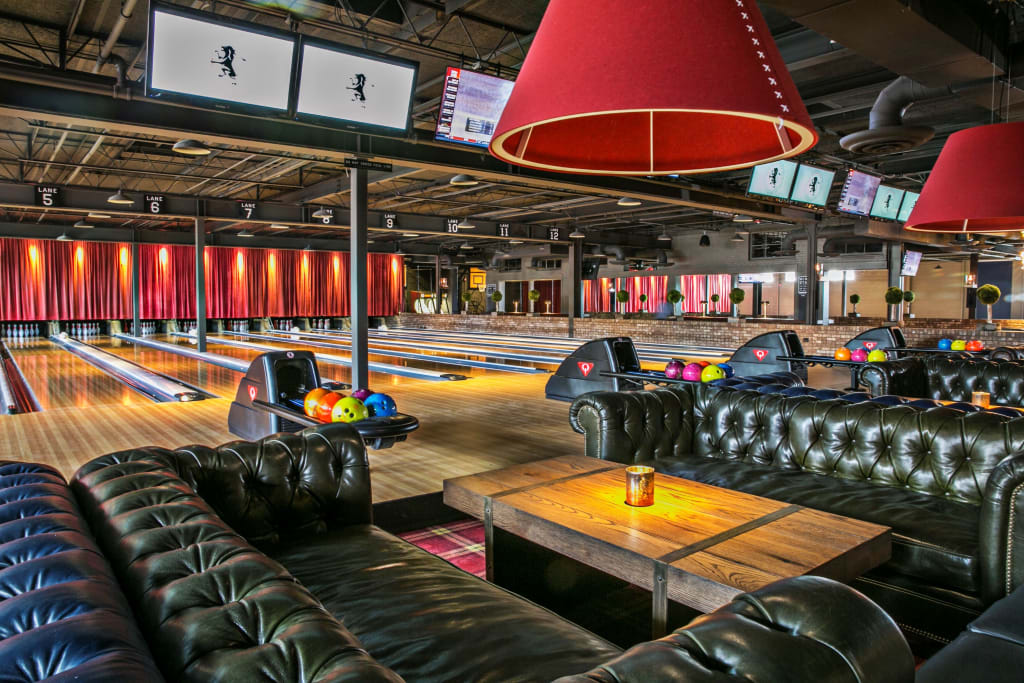 Fun Ways to Celebrate Graduation in Atlanta 3 A modern bowling alley with leather couches, wooden tables, and colorful bowling balls in Atlanta, Georgia.