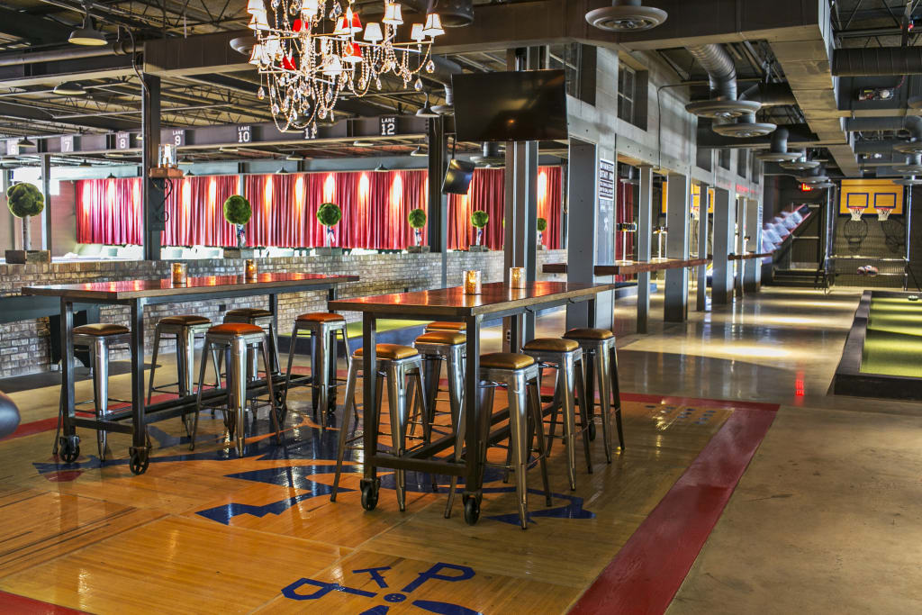 Modern industrial bar with high ceilings, chandeliers, and a basketball court in Atlanta, Georgia.