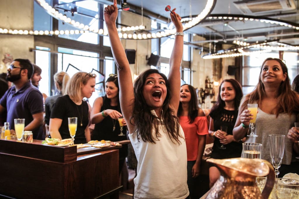 A woman celebrates with a victory gesture in a lively bar setting in Atlanta, Georgia.