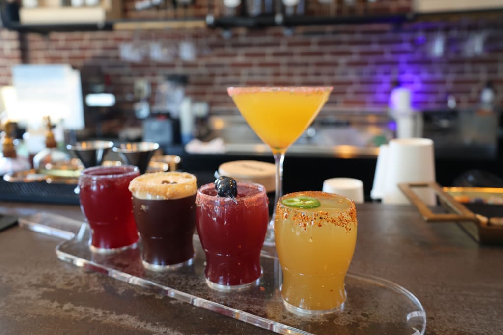 A variety of colorful cocktails, including a margarita, are displayed on a bar counter in Atlanta, Georgia.