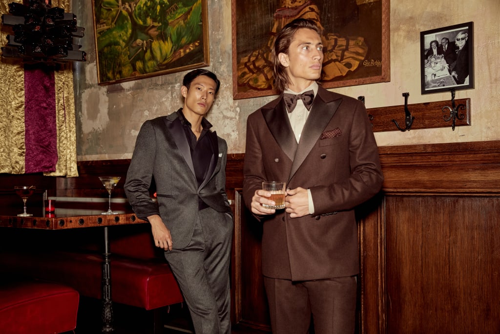 Two stylish men in suits stand in a dimly lit bar with vintage decor in Atlanta, Georgia.