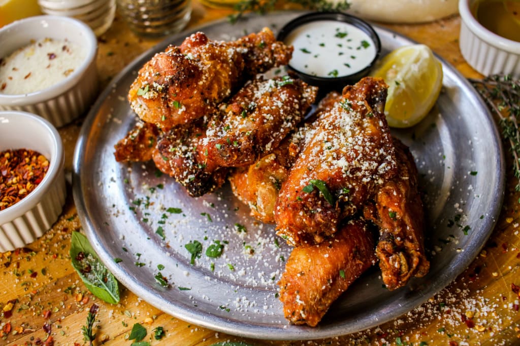Crispy chicken wings coated in Parmesan cheese and herbs, served with dipping sauces in Atlanta, Georgia.