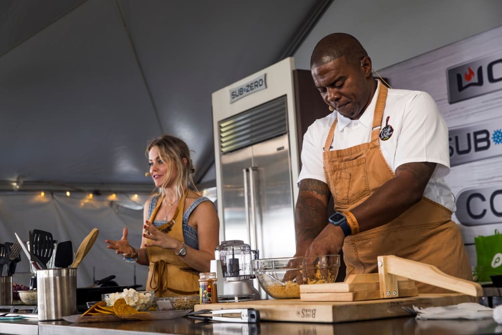 Two chefs, a man and a woman, are cooking together in a kitchen tent in Atlanta, Georgia.
