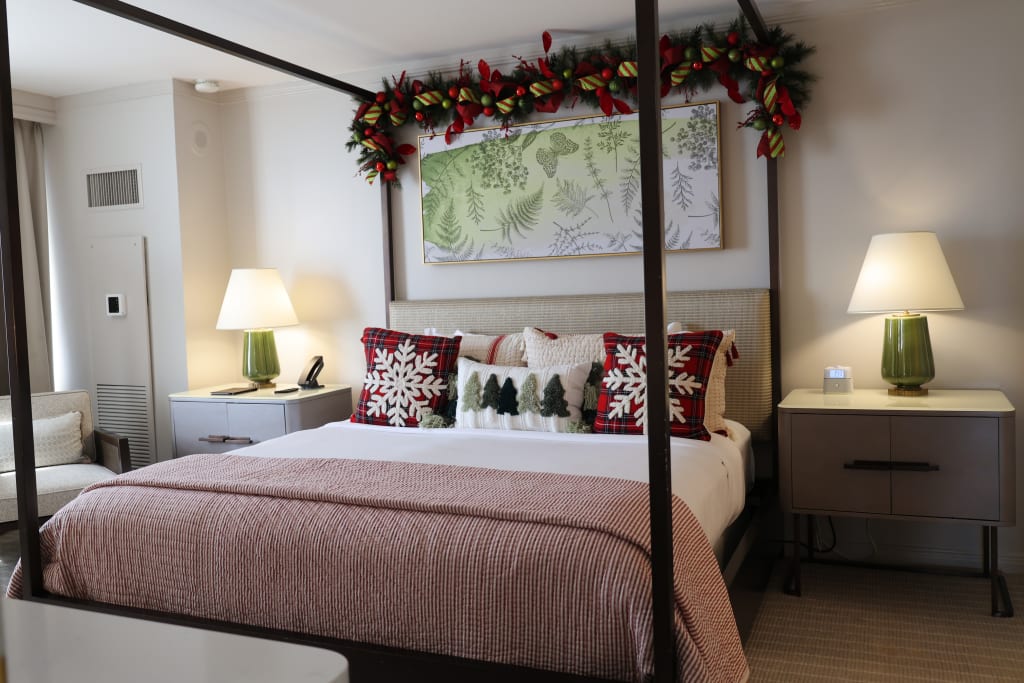 A festive bedroom with a Christmas-themed bedspread and pillows, garland above the bed, and matching lamps on either side in Atlanta, Georgia.