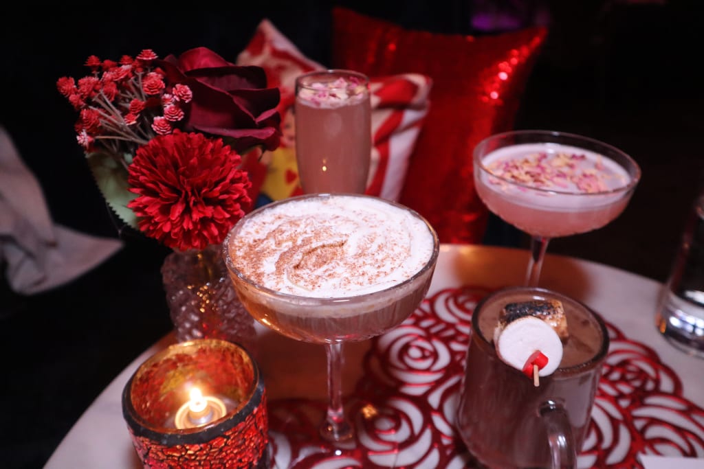 A romantic table setting with red roses, candles, and colorful cocktails in Atlanta, Georgia.