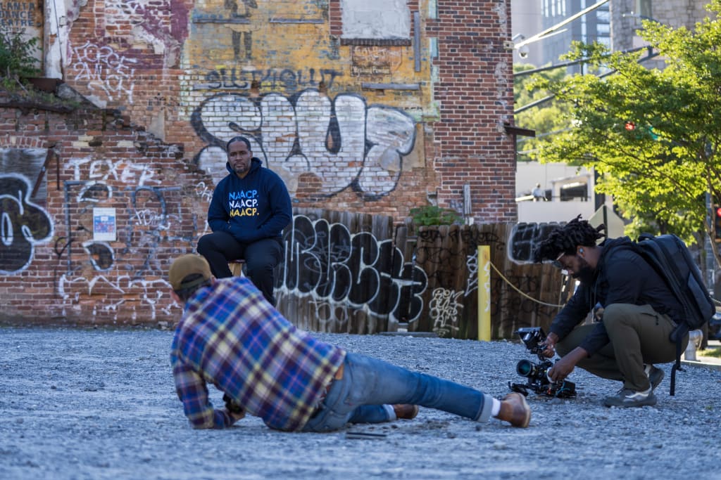 A photographer captures a portrait of a man sitting on a brick wall with graffiti in the background in Atlanta, Georgia.