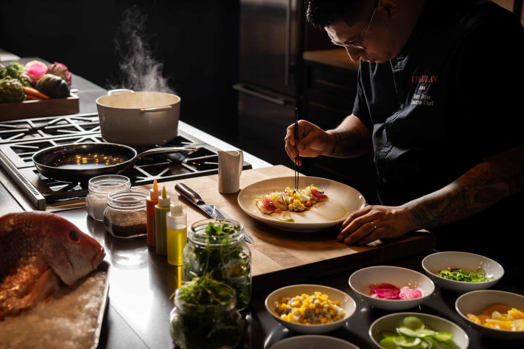 A chef is carefully plating a colorful dish in a modern kitchen with various ingredients nearby in Atlanta, Georgia.