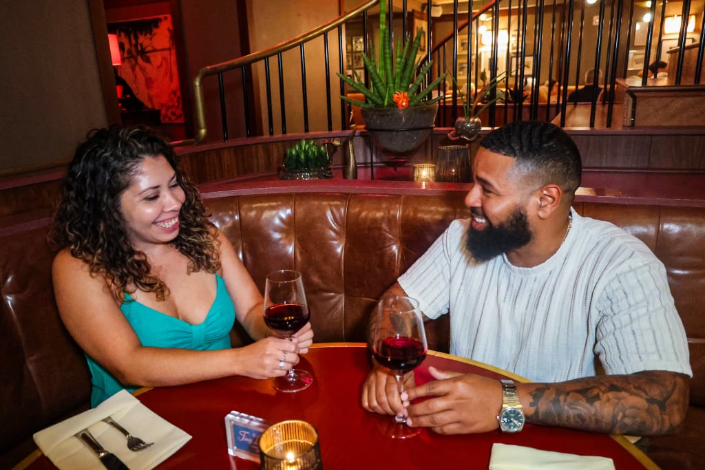 A couple enjoys a romantic dinner at a restaurant, sipping red wine and smiling at each other in Atlanta, Georgia.