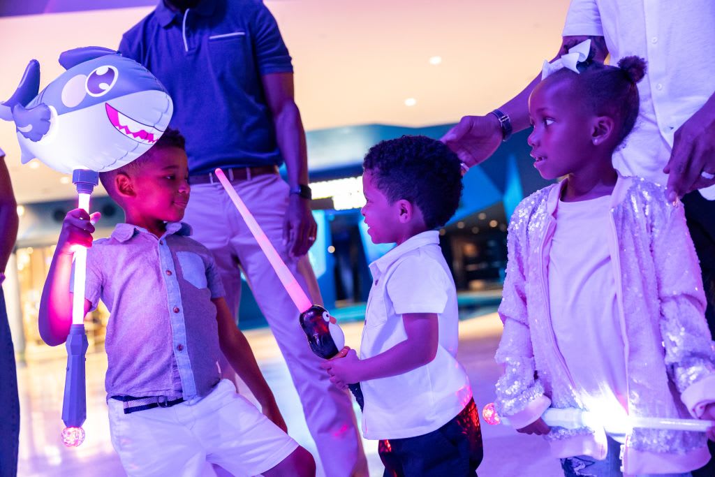 @DiscoverAtlanta Link In Bio 54 Children playfully wield light-up toys in a brightly lit indoor space in Atlanta, Georgia.