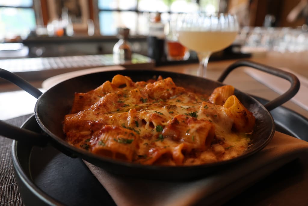 A cast iron skillet filled with baked pasta, cheese, and tomato sauce, garnished with herbs in Atlanta, Georgia.