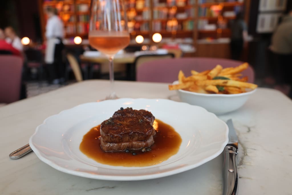A plate of steak with gravy and a side of fries, accompanied by a glass of rosé wine in Atlanta, Georgia.