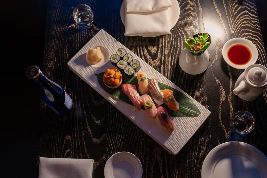 Ultimate Guide to Hotel Dining ATL Style 20 Assorted sushi and sashimi on a black wooden table with soy sauce and wasabi in Atlanta, Georgia.