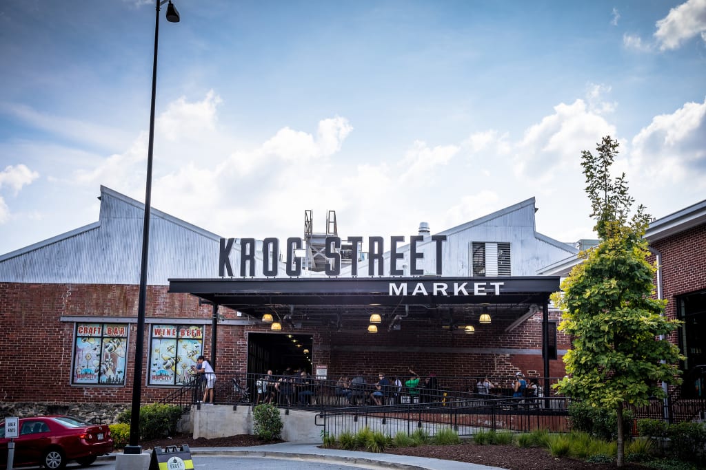 Shopping at Krog Street Market 1 A bustling outdoor market with a large sign reading 'Krog Street Market' above an entrance in Atlanta, Georgia.