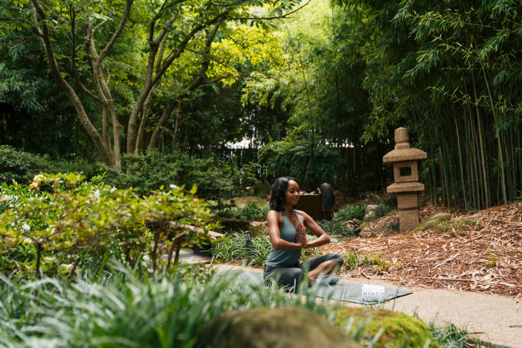A woman practices yoga in a serene garden surrounded by lush greenery and bamboo in Atlanta, Georgia.