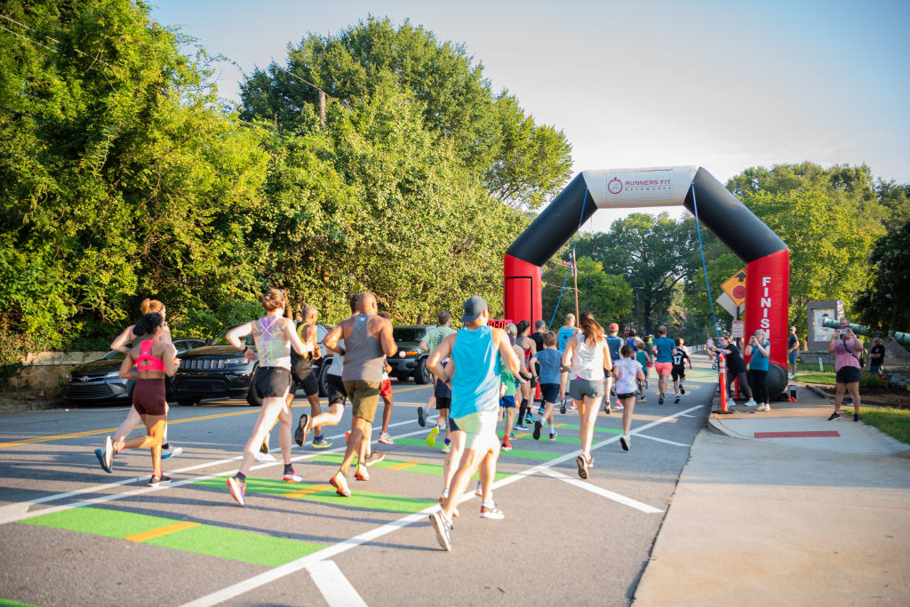 A group of runners approach the finish line of a race, passing under an inflatable arch in Atlanta, Georgia.