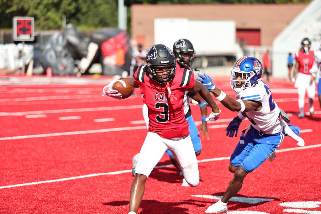 Football players in red and blue uniforms chase each other on a red field in Atlanta, Georgia.