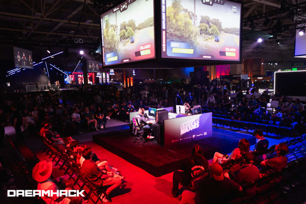A large crowd watches a live esports event with multiple screens displaying gameplay in Atlanta, Georgia.