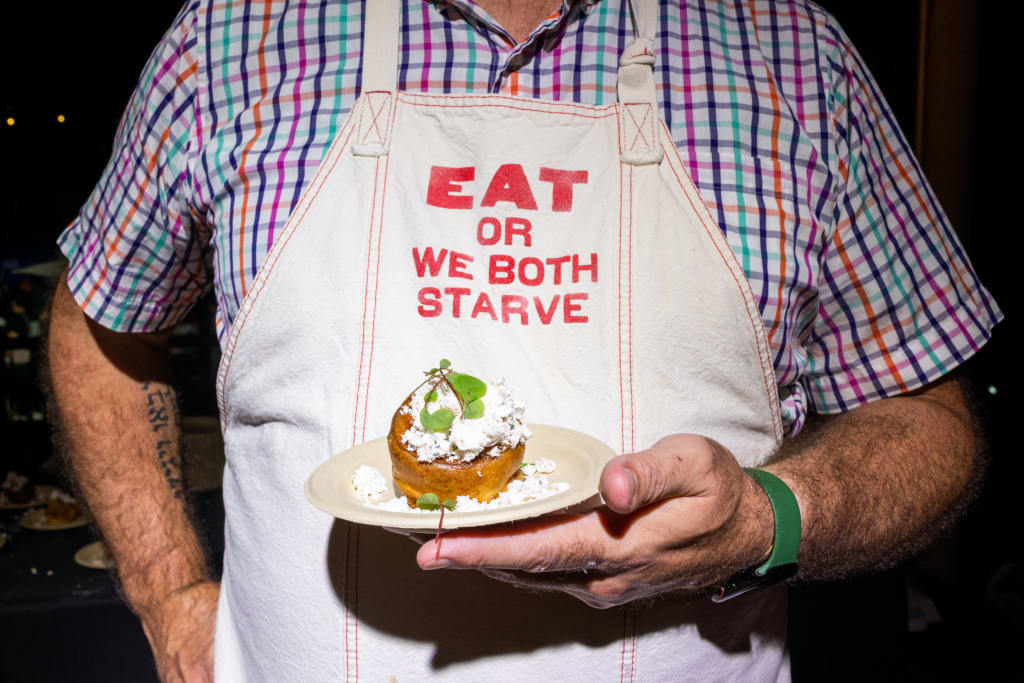 Taste Atlanta’s International Food Culture at the 2025 Food & Wine Festival 1 A man in a colorful apron holds a small plate with a single bite-sized dessert in Atlanta, Georgia.
