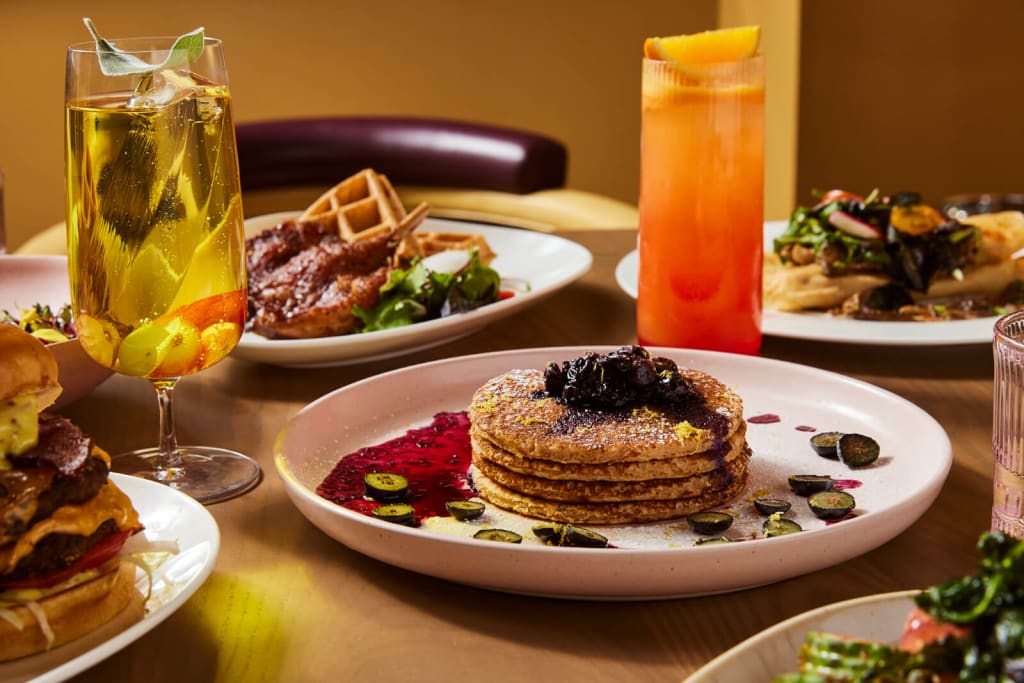 Guide to The Best Luxury Hotels in Atlanta 22 A vibrant restaurant table setting with colorful cocktails, waffles, burgers, and salads in Atlanta, Georgia.