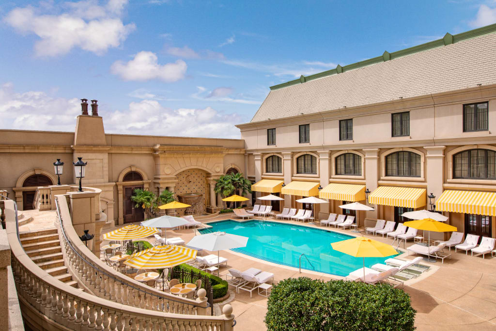Guide to The Best Luxury Hotels in Atlanta 14 Luxurious outdoor pool area with yellow umbrellas and lounge chairs surrounded by elegant architecture in Atlanta, Georgia.