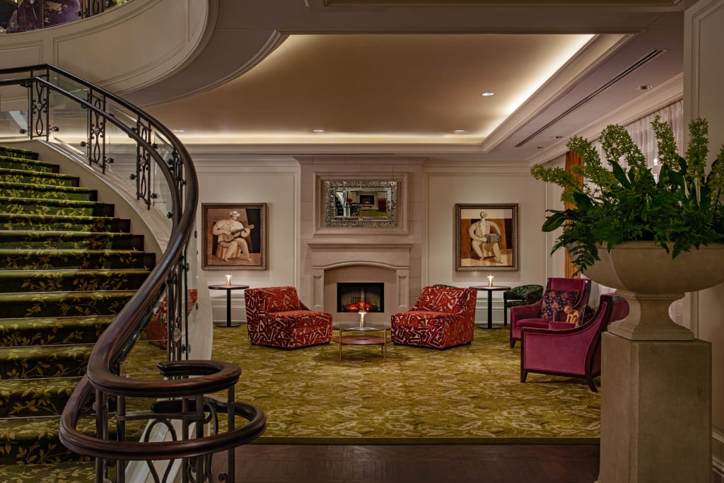 Guide to The Best Luxury Hotels in Atlanta 13 An elegant hotel lobby with a curved staircase, fireplace, and plush seating in Atlanta, Georgia.