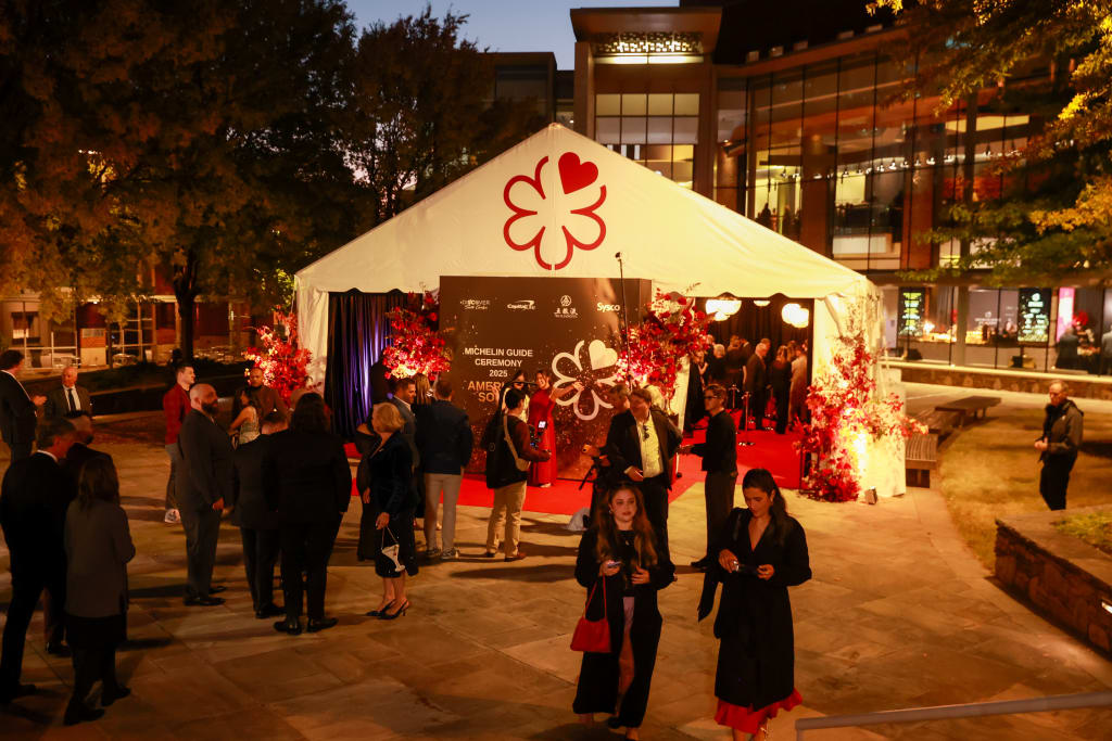 Crowd gathered under a large white tent with a red clover logo for an evening event in Atlanta, Georgia.
