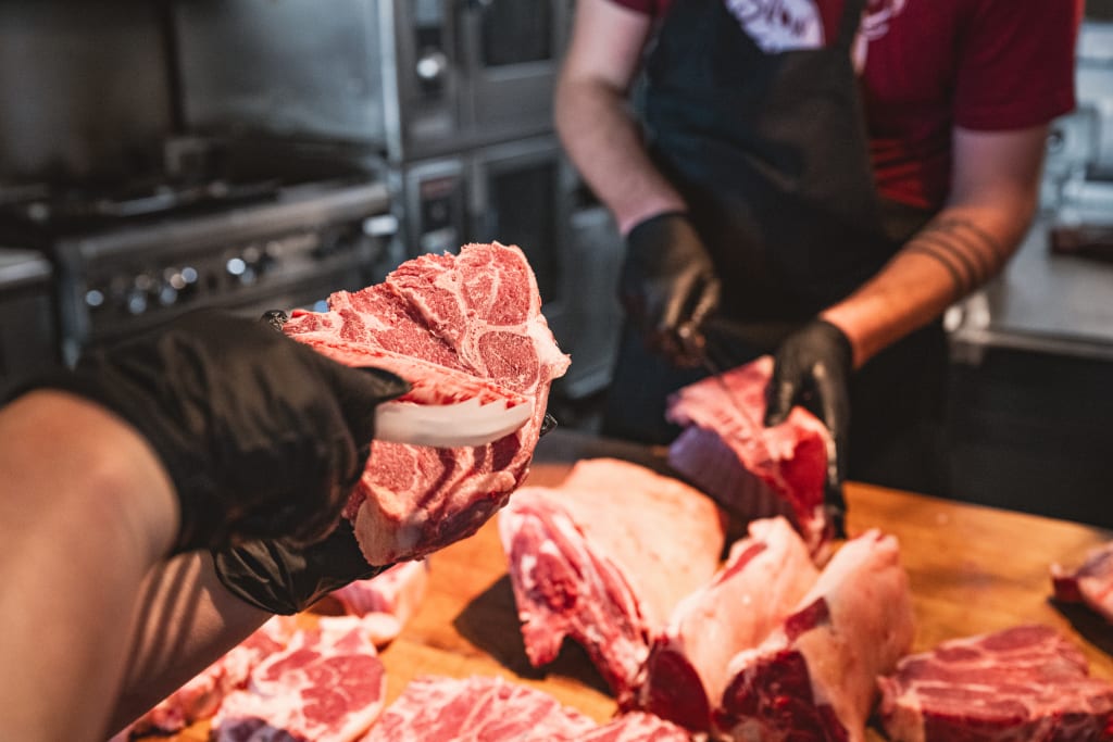 Atlanta Winter Gift Guide 7 Two butchers in a kitchen preparing raw meat on a wooden table in Atlanta, Georgia.