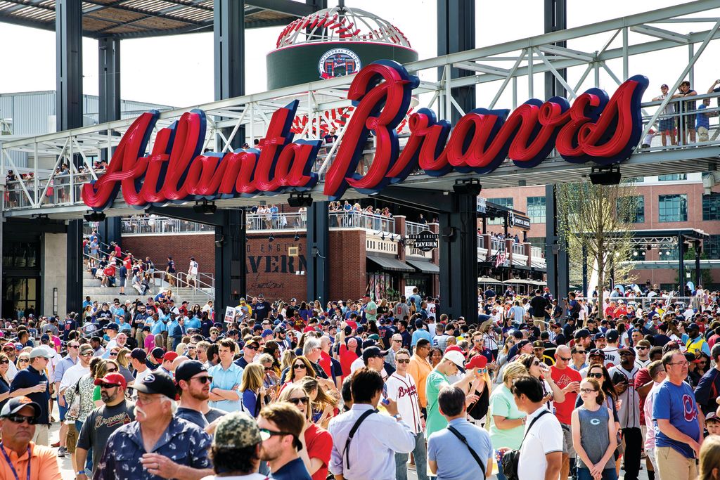 A large crowd gathers at the entrance of a baseball stadium, with a prominent sign reading 'Atlanta Braves' in Atlanta, Georgia.