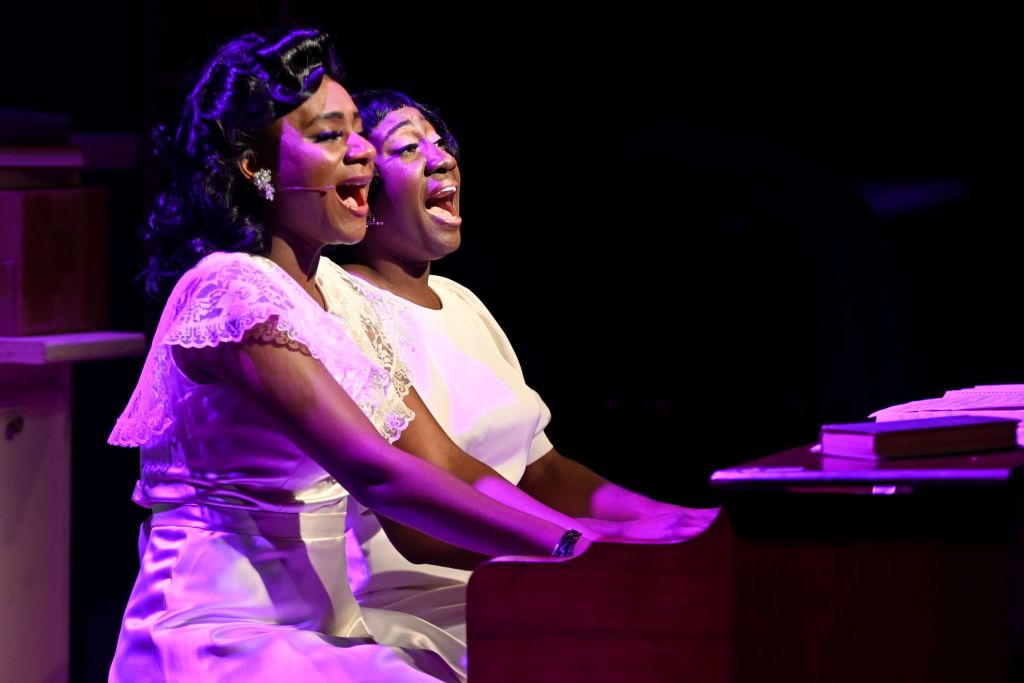 Two women singing at a piano from Kenny Leon's True Colors Theatre Company. 