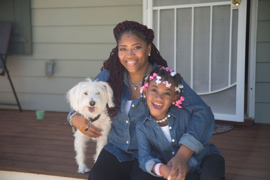 Mom and daughter posing with a white dog.