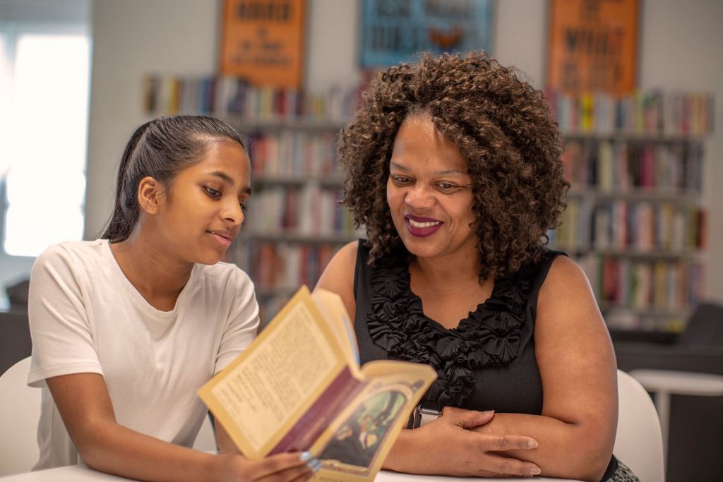 Two women reading a book.