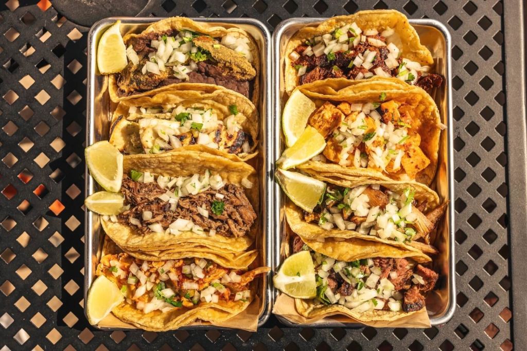 Two trays of colorful, freshly made tacos with various fillings and lime wedges in Atlanta, Georgia.