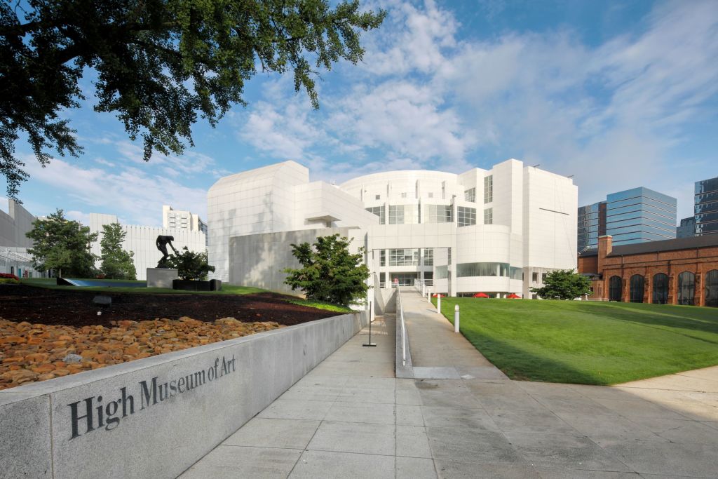 A modern white building with a curved roof and glass windows, surrounded by green grass and trees in Atlanta, Georgia.