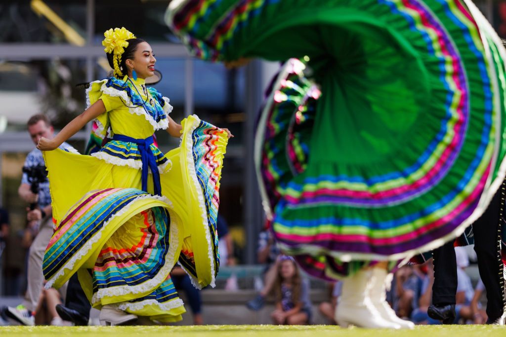 Two women in vibrant, colorful traditional dresses dance energetically outdoors in Atlanta, Georgia.