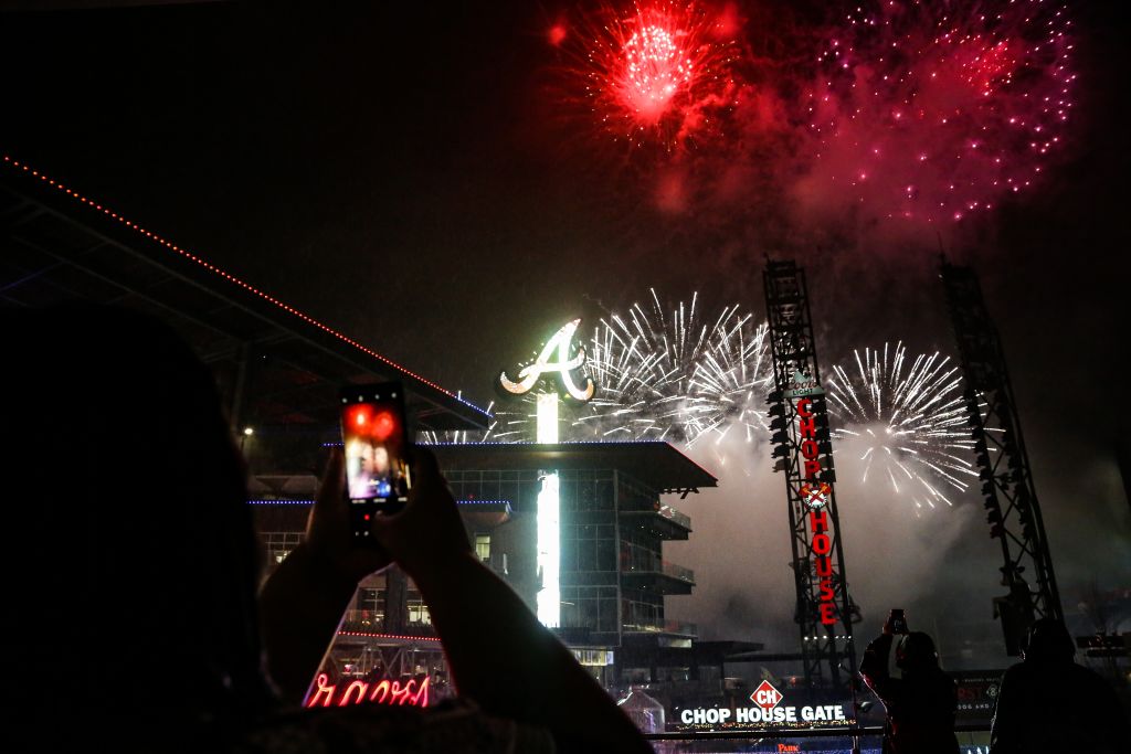 Fireworks explode over a stadium with a large 'A' sign, as fans capture the moment on their phones in Atlanta, Georgia.