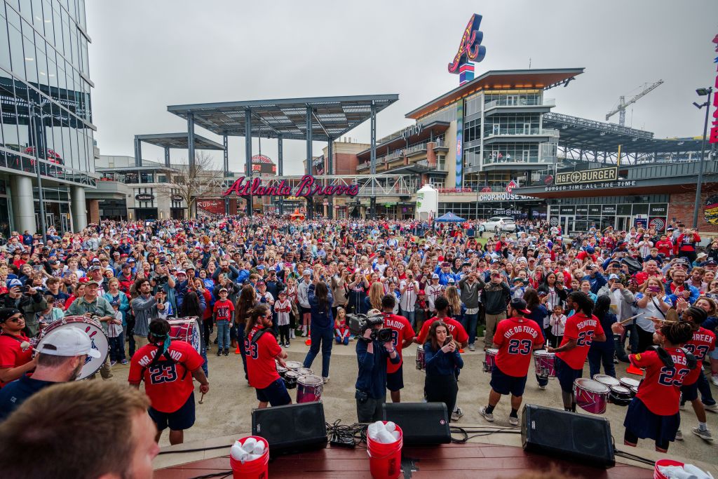 A large crowd of people in red shirts gathers in a stadium, cheering and playing drums in Atlanta, Georgia.