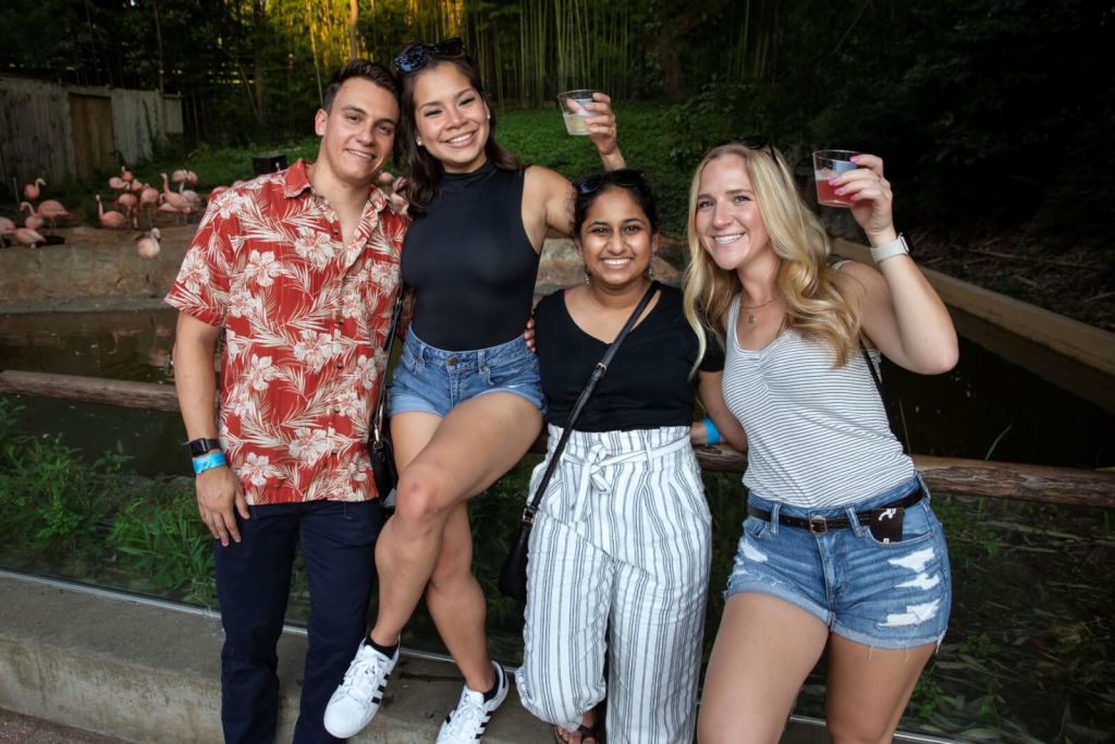 Four friends, two men and two women, pose together outdoors with drinks in hand, smiling in Atlanta, Georgia.