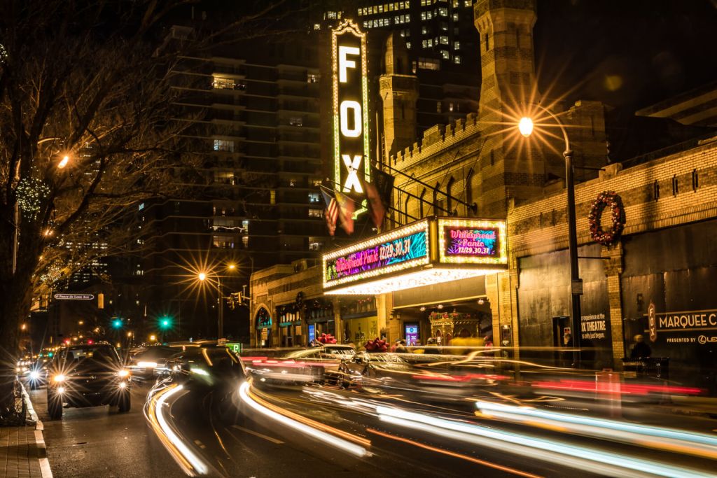 Cars drive by the Fox Theatre marquee at night