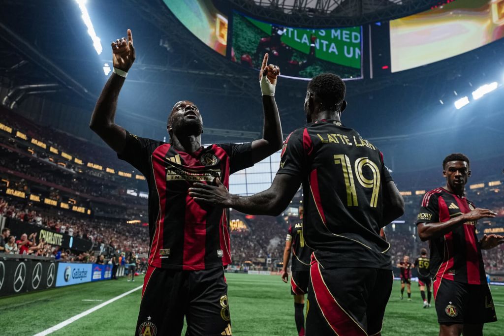 Soccer players celebrate a goal with raised fists in a packed stadium in Atlanta, Georgia.
