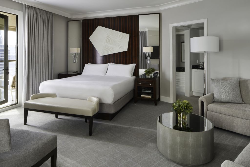 Where to Stay Near Atlanta Airport 4 Modern hotel room with king bed, sofa, coffee table, and balcony access in Atlanta, Georgia.