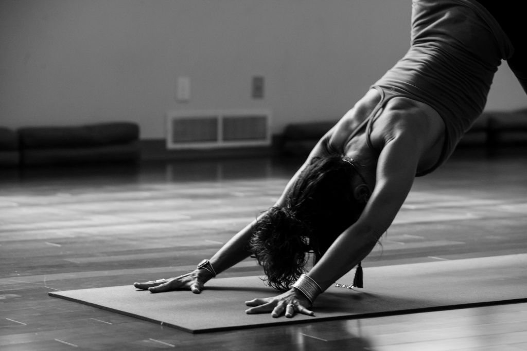 Ultimate Guide to Hispanic Heritage Month in Atlanta 2 A woman performs a yoga pose on a mat in a studio, balancing on her hands and feet in Atlanta, Georgia.