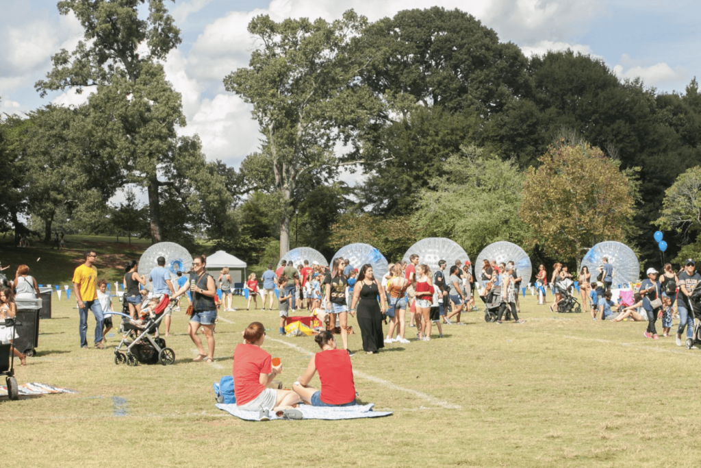 Cool Things To Do in October in Atlanta 2 Outdoor festival with people enjoying activities on a grassy field, including giant inflatable balls in Atlanta, Georgia.