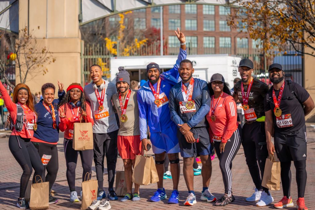 A group of diverse runners celebrate their marathon finish with medals and goodie bags in Atlanta, Georgia.