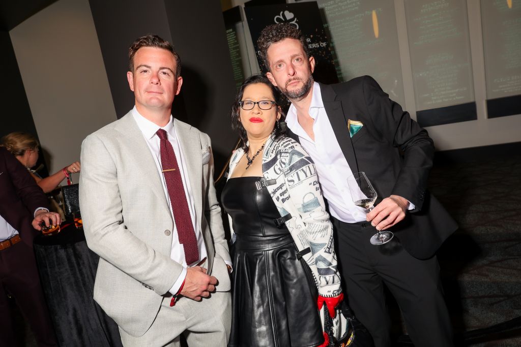 Three stylishly dressed individuals pose together at a formal event in Atlanta, Georgia.