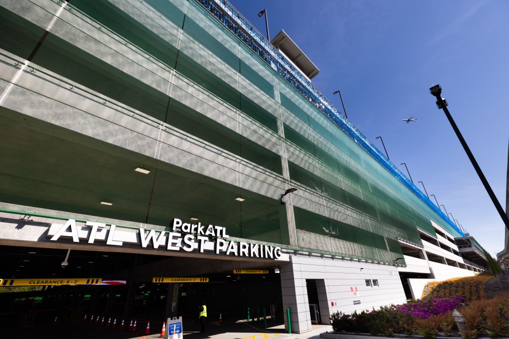 A modern, multi-story parking garage with a green facade and clear signage indicating 'ParkATL West Parking' near the entrance in Atlanta, Georgia.