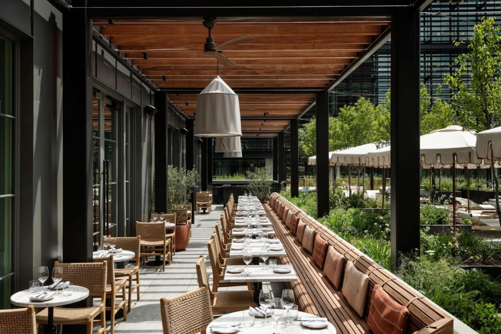 A modern outdoor restaurant with a wooden pergola, wicker furniture, and lush greenery in Atlanta, Georgia.