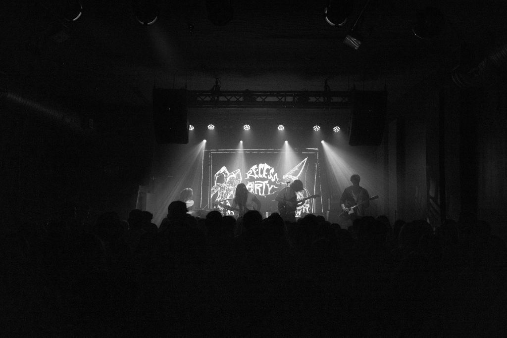 A band performs on a dimly lit stage, with bright stage lights highlighting the musicians and their instruments in Atlanta, Georgia.